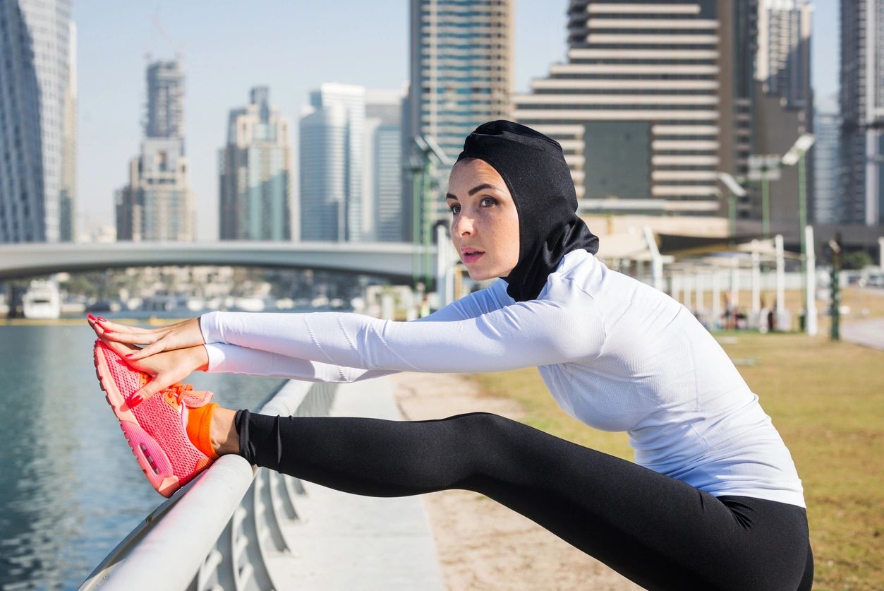 Woman stretching outdoors by the waterfront — active wellness and women's health